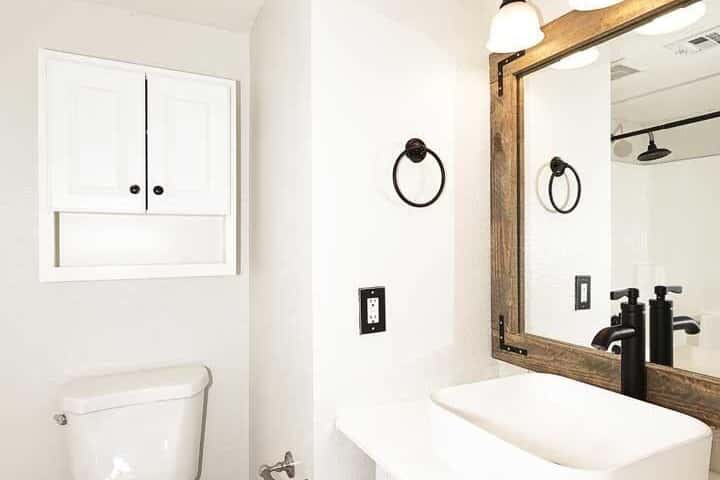 17 of 29. Freshly updated bathroom with contemporary fixtures, decorative mirror, and modern lighting. Neutral finishes and clean lines create a polished appearance.