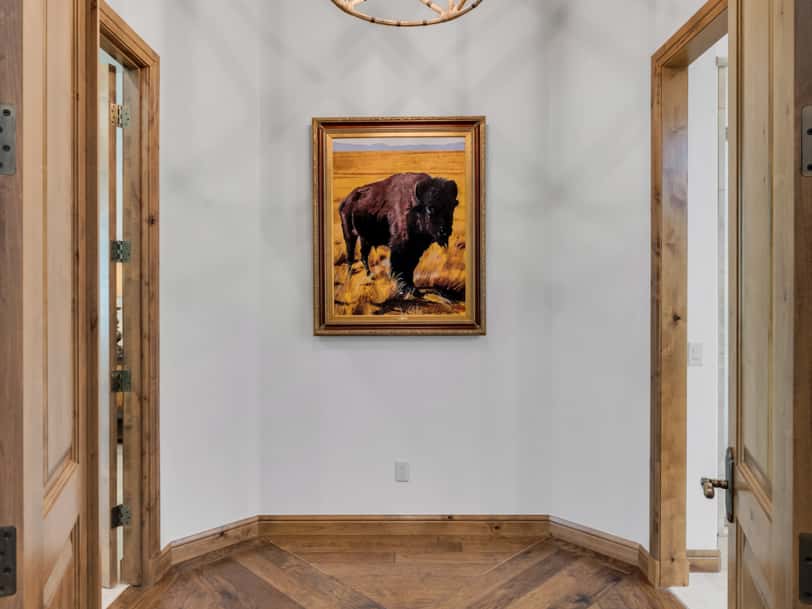 15 of 52. Elegant hallway with statement chandelier, custom wood flooring, and upscale architectural details leading into the luxurious primary suite retreat.
