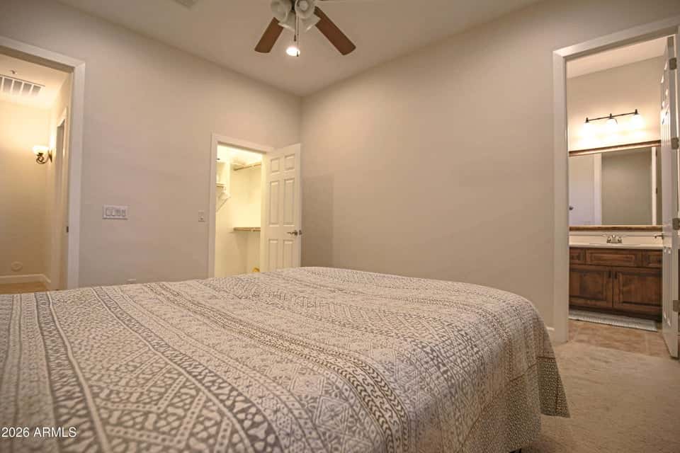 40 of 72. A comfortable secondary bedroom featuring plush carpeting, a ceiling fan, and convenient access to the adjacent bathroom. A flexible living space ideal for guests, family members, or a home office in Scottsdale.